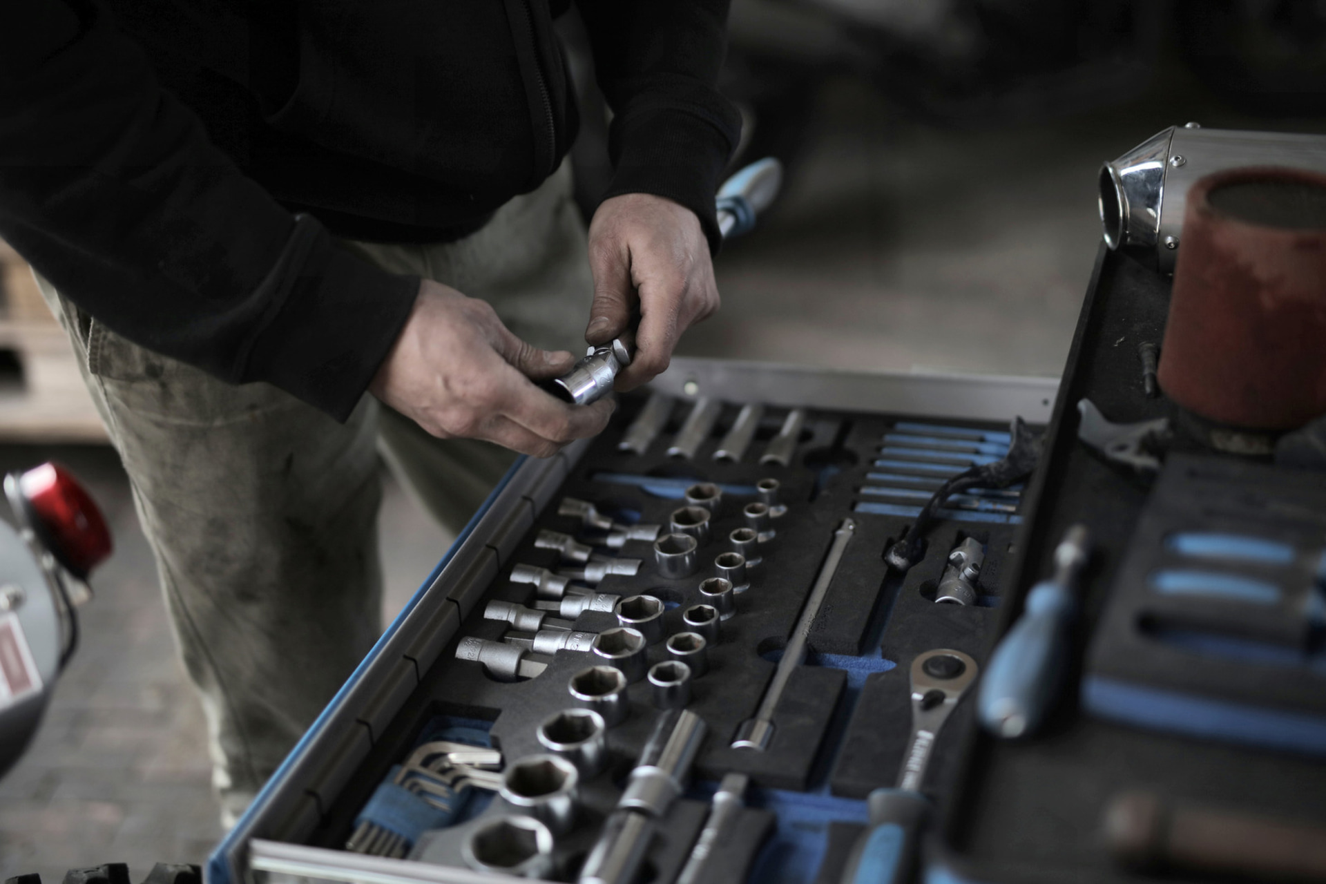 Hands selecting a socket from an organized toolbox