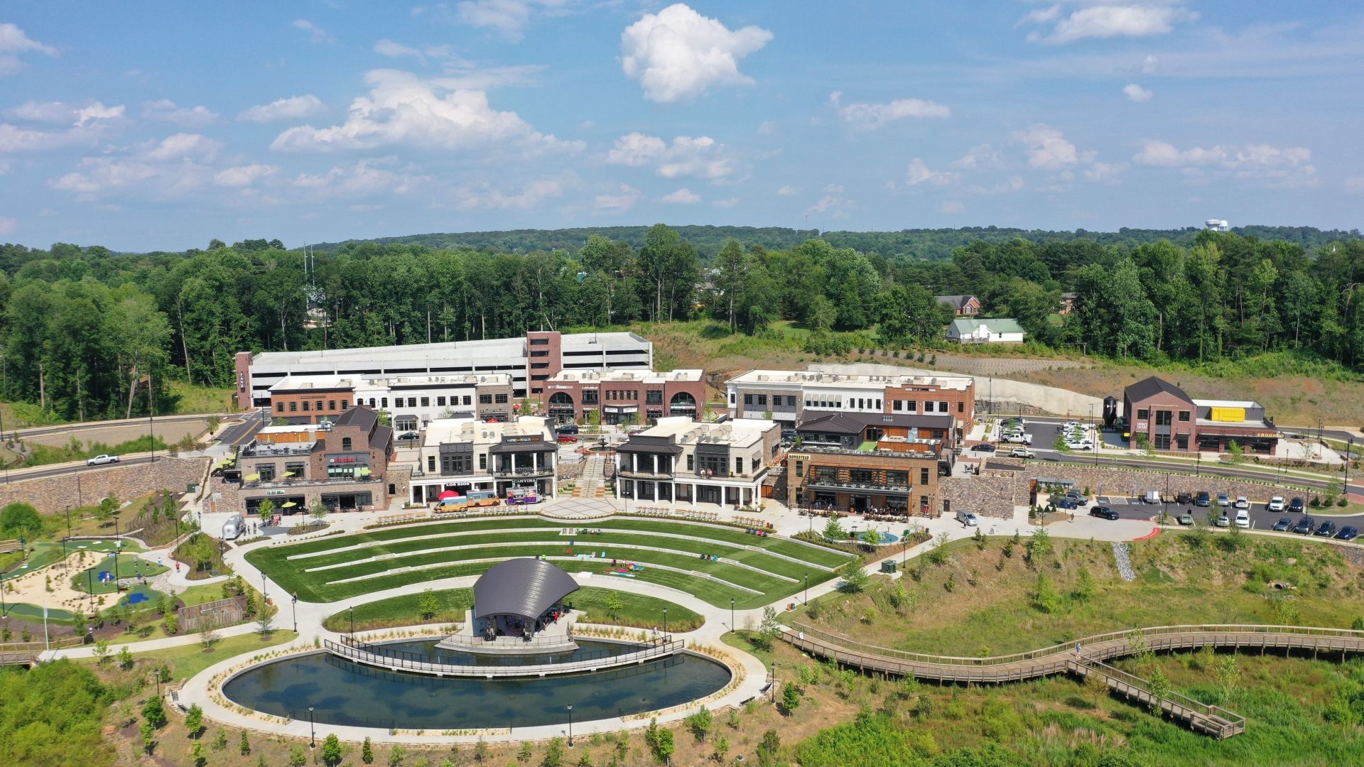 Aerial view of a commercial development with amphitheater, retail strip, and reflecting pond