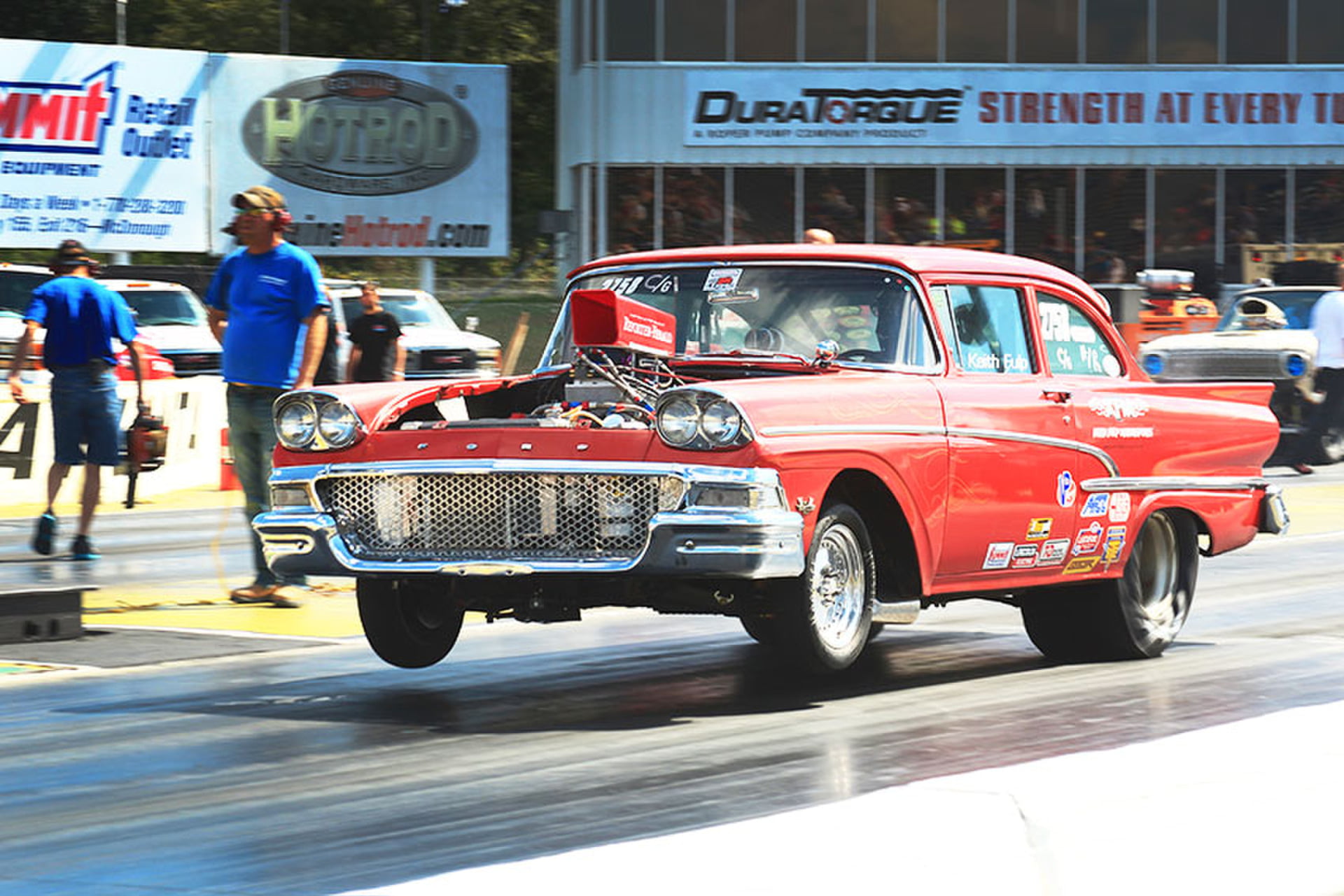 1958 Ford drag car launching off the line, front wheels up